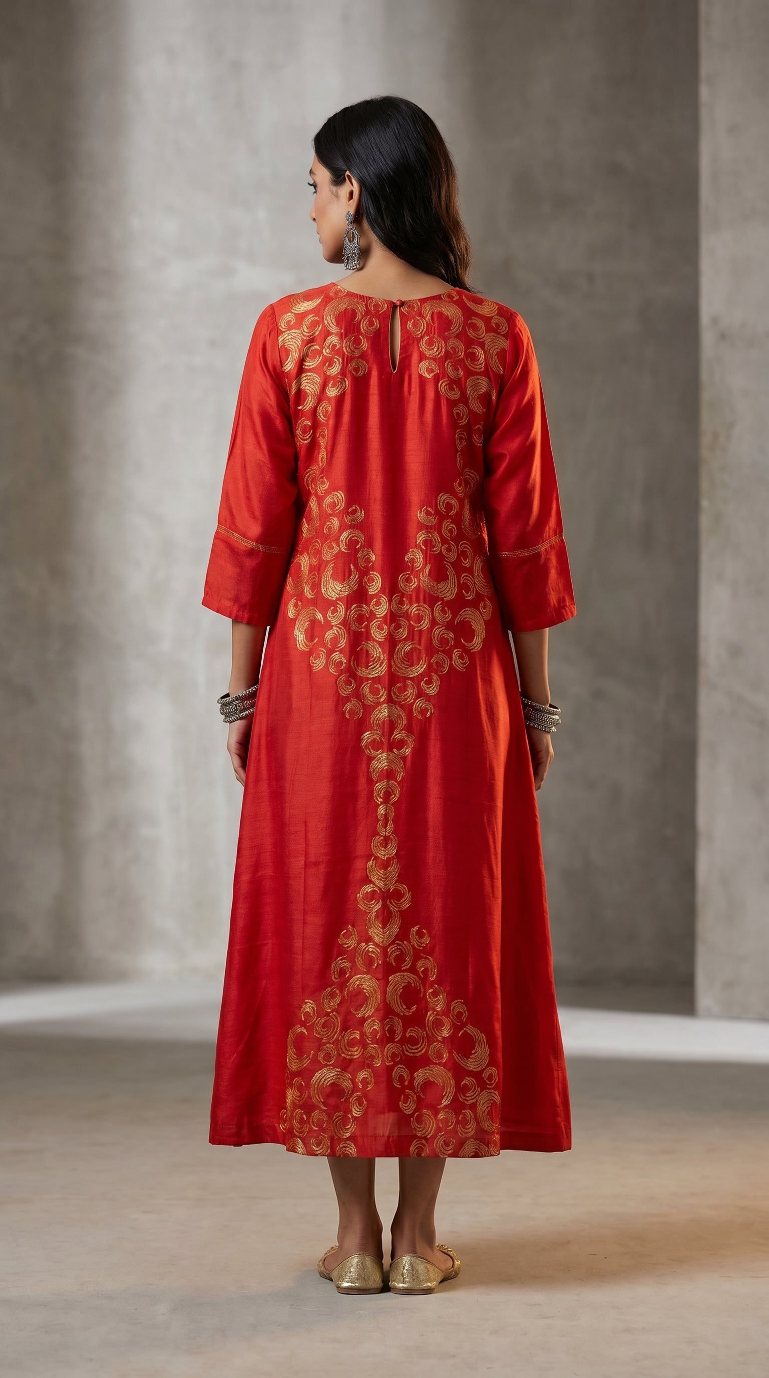 Woman wearing a red embroidered dress against a neutral background