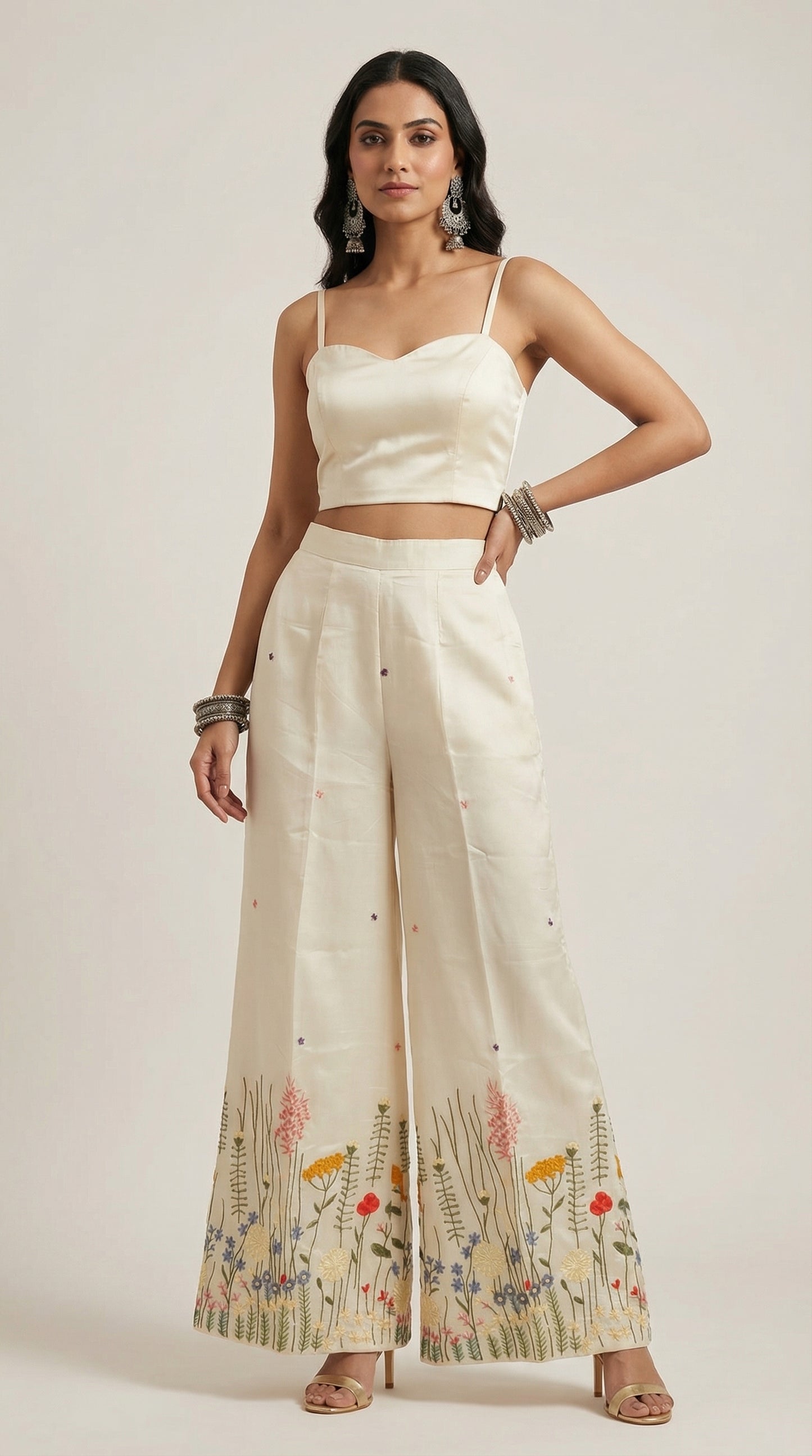 Woman wearing a white outfit with floral plazzo on a plain background