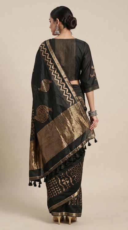 Woman wearing a black and gold saree with intricate patterns on a beige background