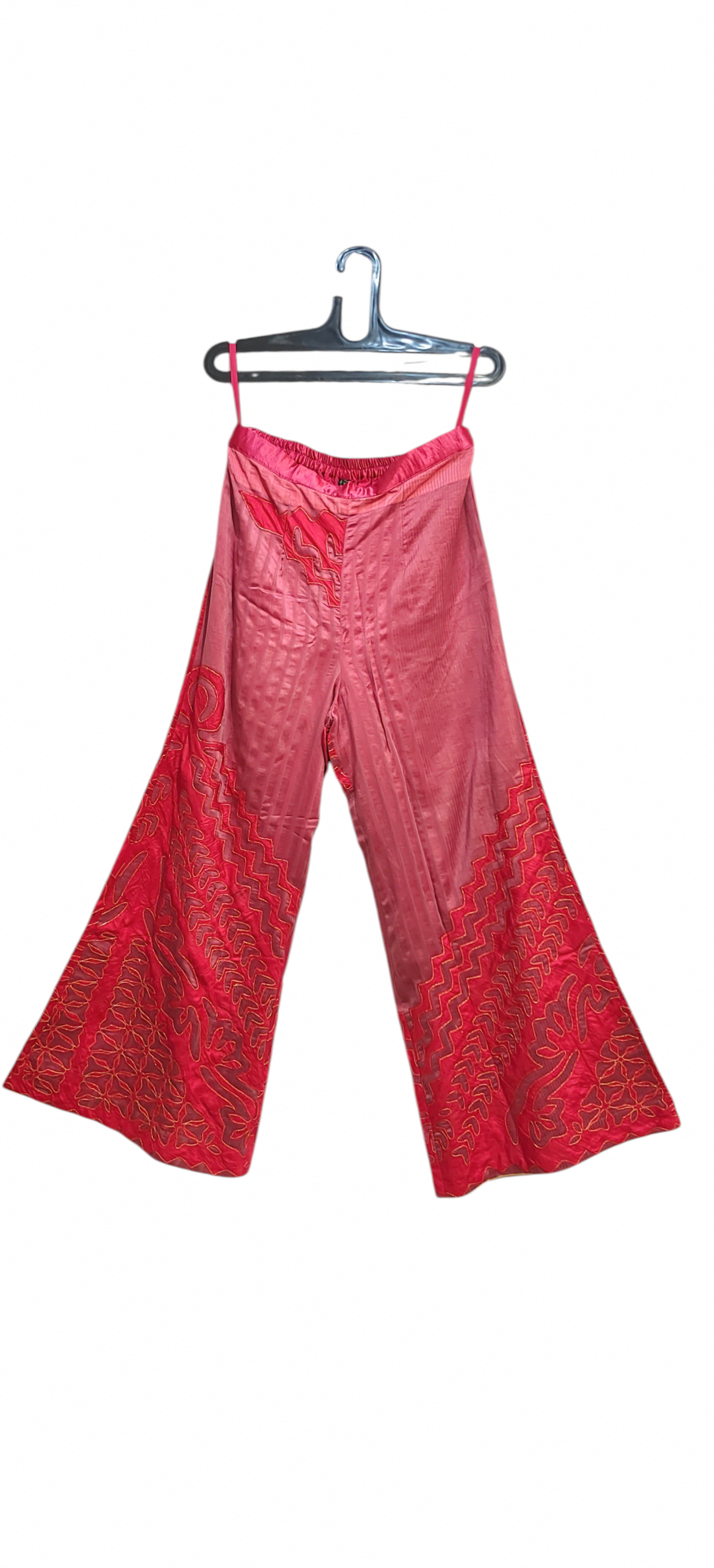 Pink patterned pants on a hanger against a white background