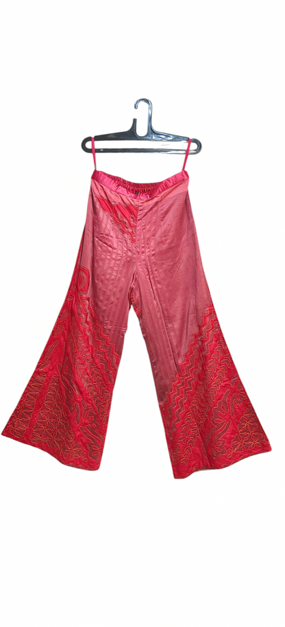 Pink patterned pants on a hanger against a white background