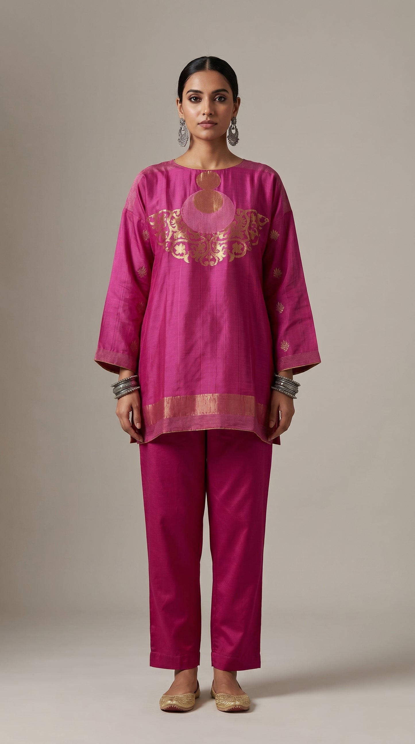 Woman wearing a magenta traditional outfit with gold embroidery on a beige background