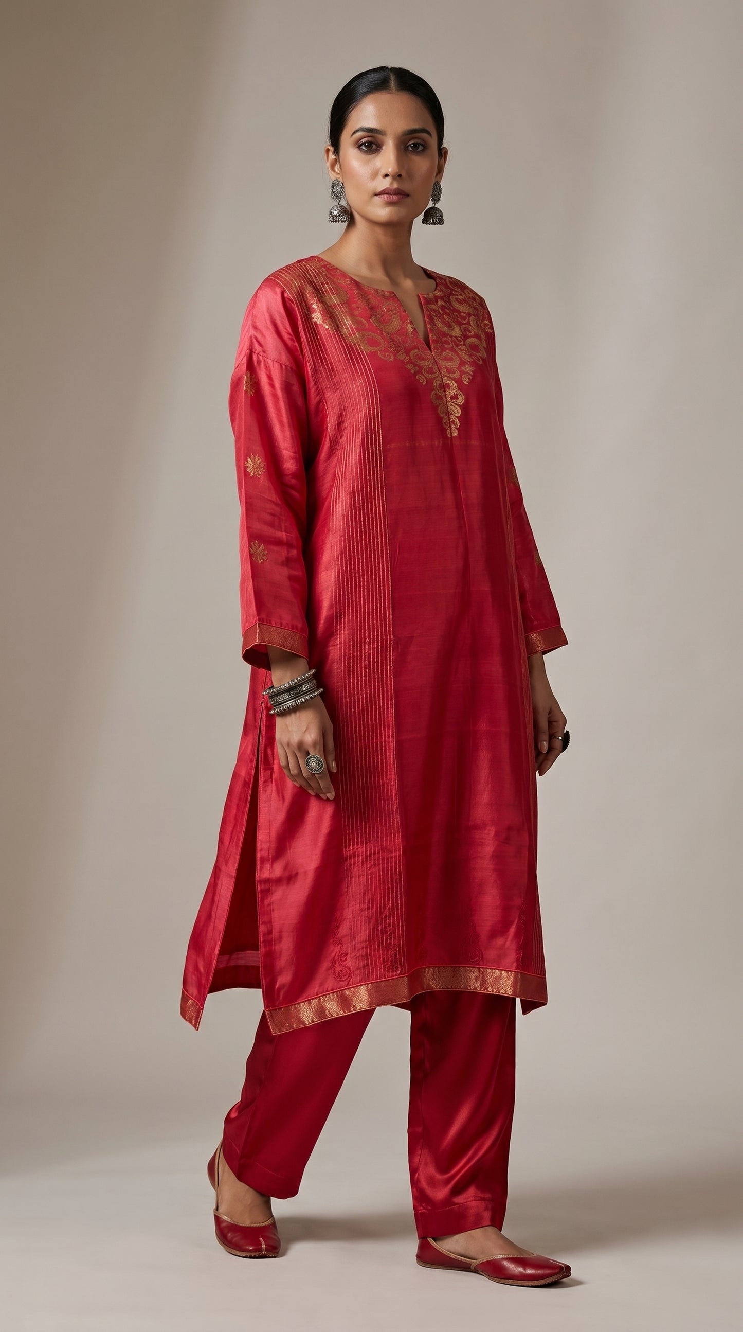 Woman wearing a red traditional kurta with gold embroidery on a beige background