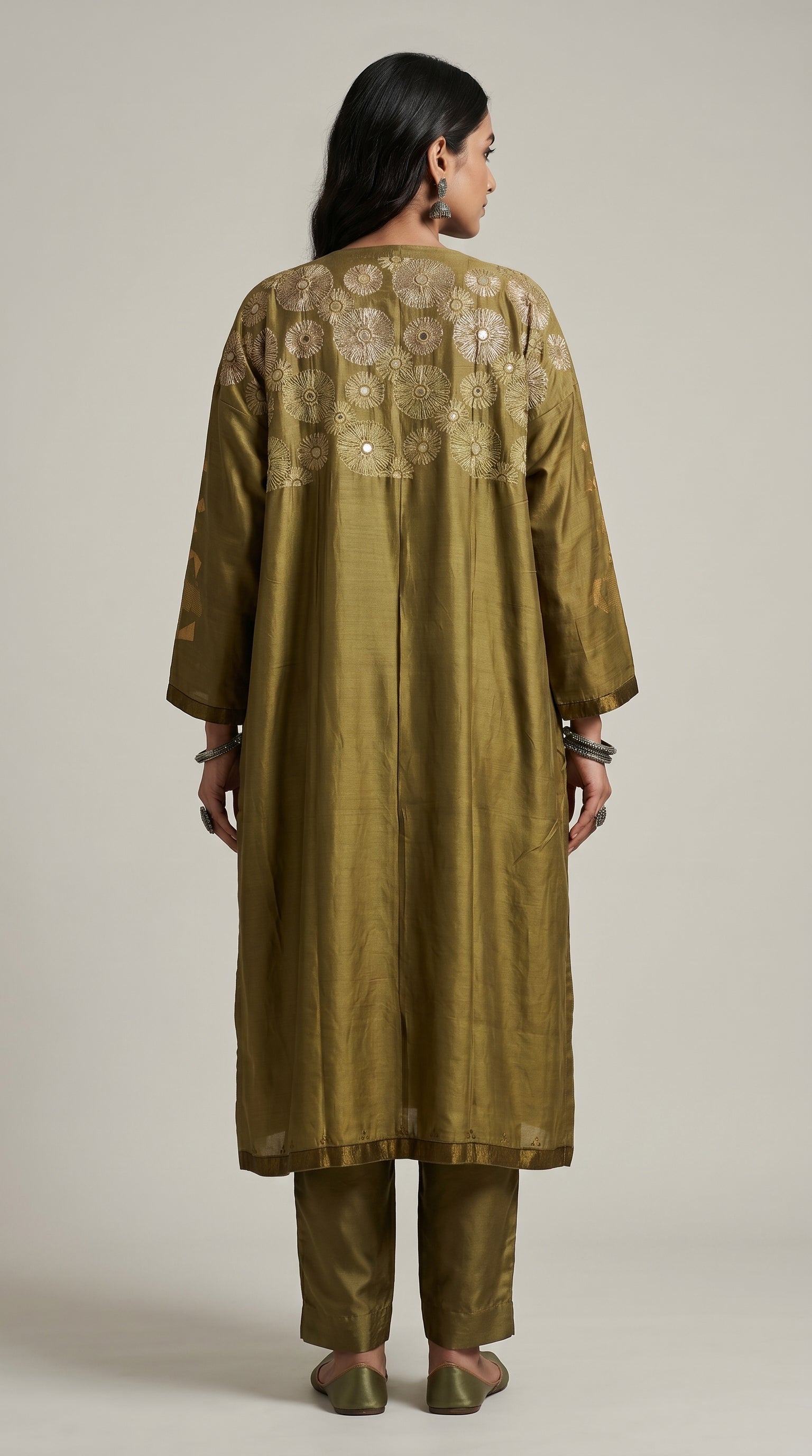 Woman wearing a green embroidered kurta with pants on a plain background