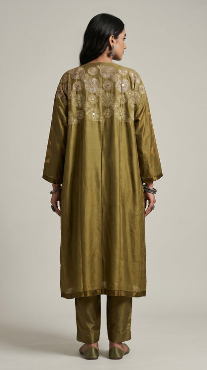 Woman wearing a green embroidered kurta with pants on a plain background