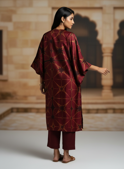 Woman wearing a patterned maroon kurta and architectural setting.