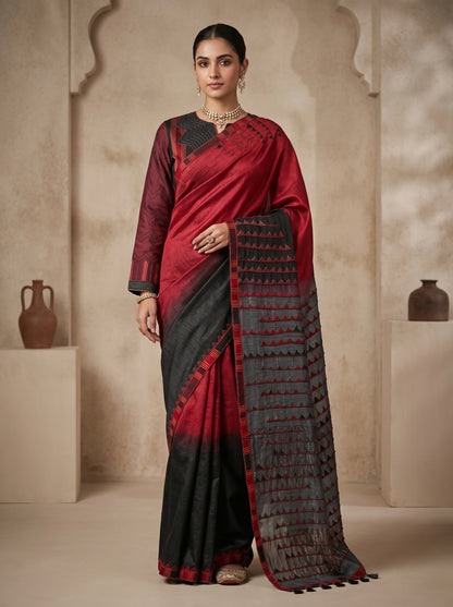 Woman wearing a red and black saree with a patterned border against a neutral background
