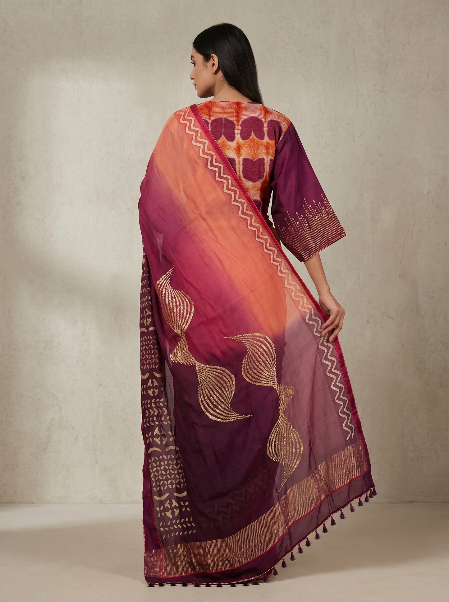 Woman wearing a colorful saree with intricate patterns on a plain background