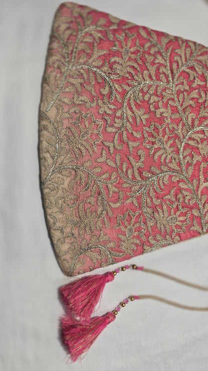 Decorative pink and gold handbag pouch with tassels on a white background