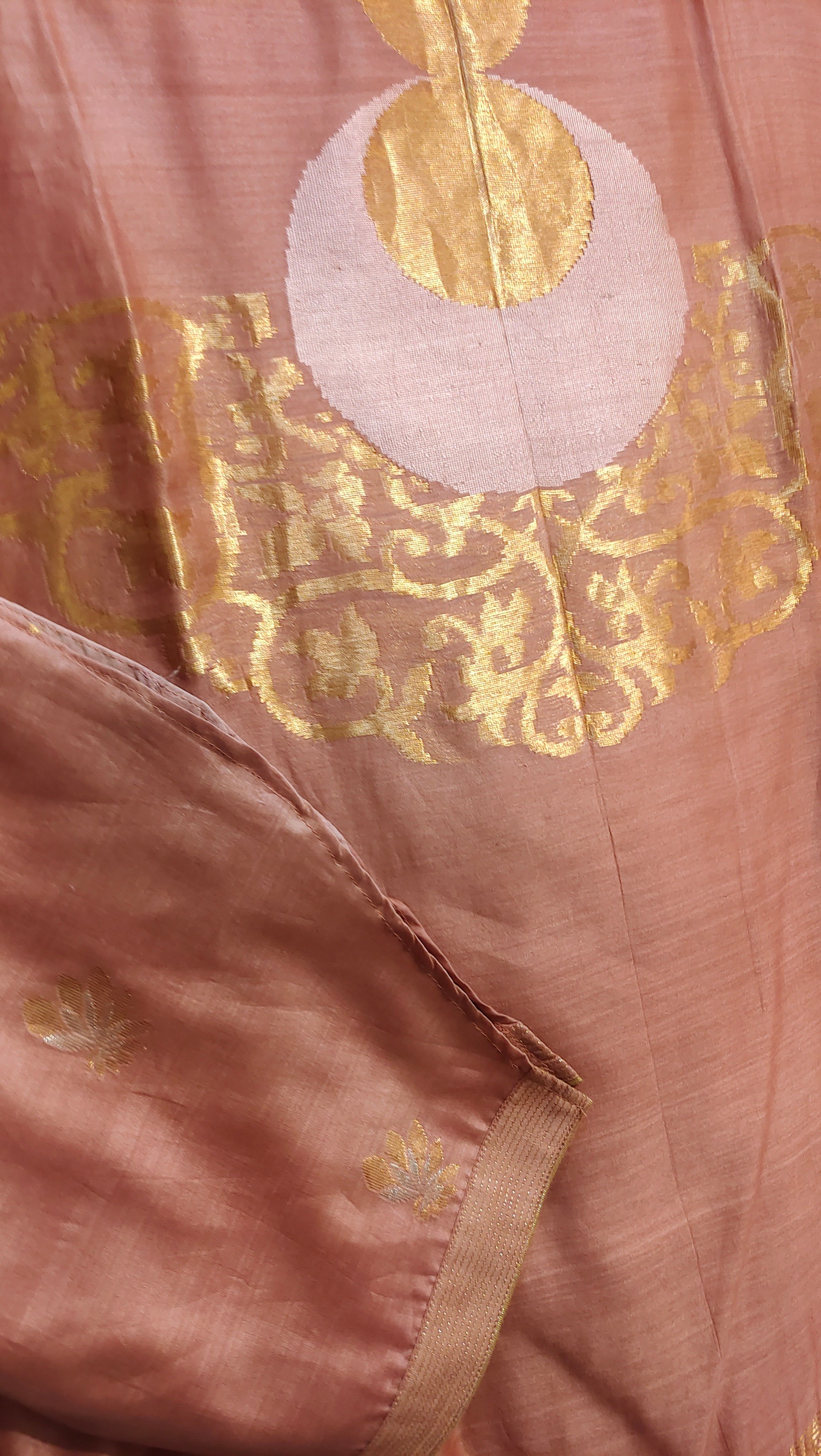 Close-up of a pink fabric with gold and white circular patterns