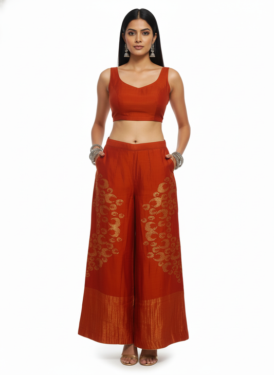 Woman wearing a traditional plazzo pant with a rust top and on a white background